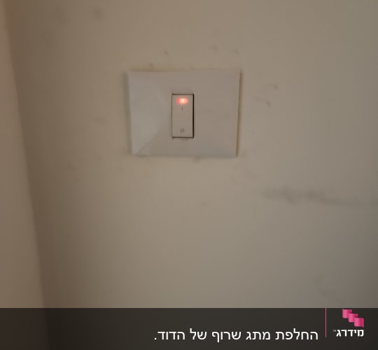 מתג עם נורית חיווי אדומה על קיר